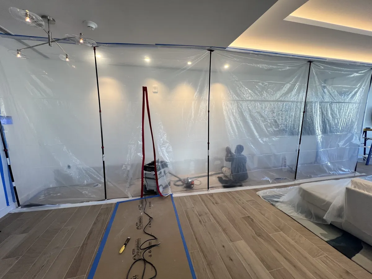 Dust containment: plastic zip-wall enclosure with a dust-extracting vacuum while a wall is sanded