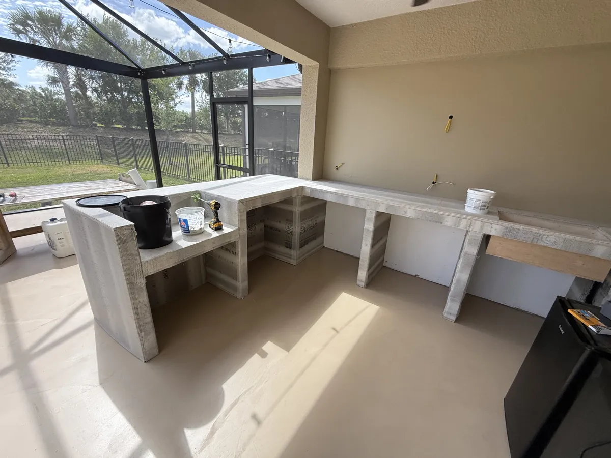 Before: L-shaped outdoor kitchen frame built in cement board with mesh tape on a screened lanai
