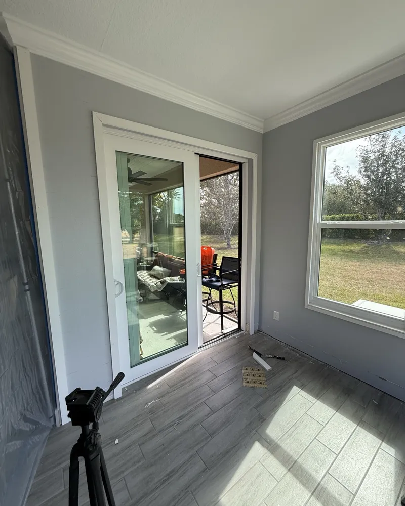 Before: Florida room with plain gray painted walls, sliding door and window