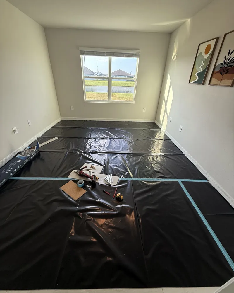 During: bedroom subfloor covered with black underlayment, tools and first planks laid out