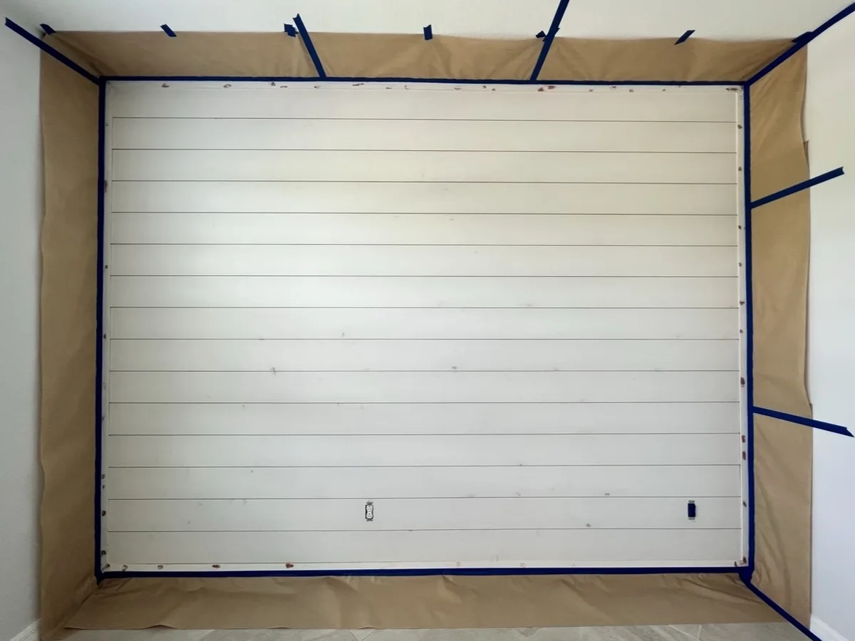 During: new shiplap accent wall installed, nail holes filled and surrounding walls masked with paper and tape