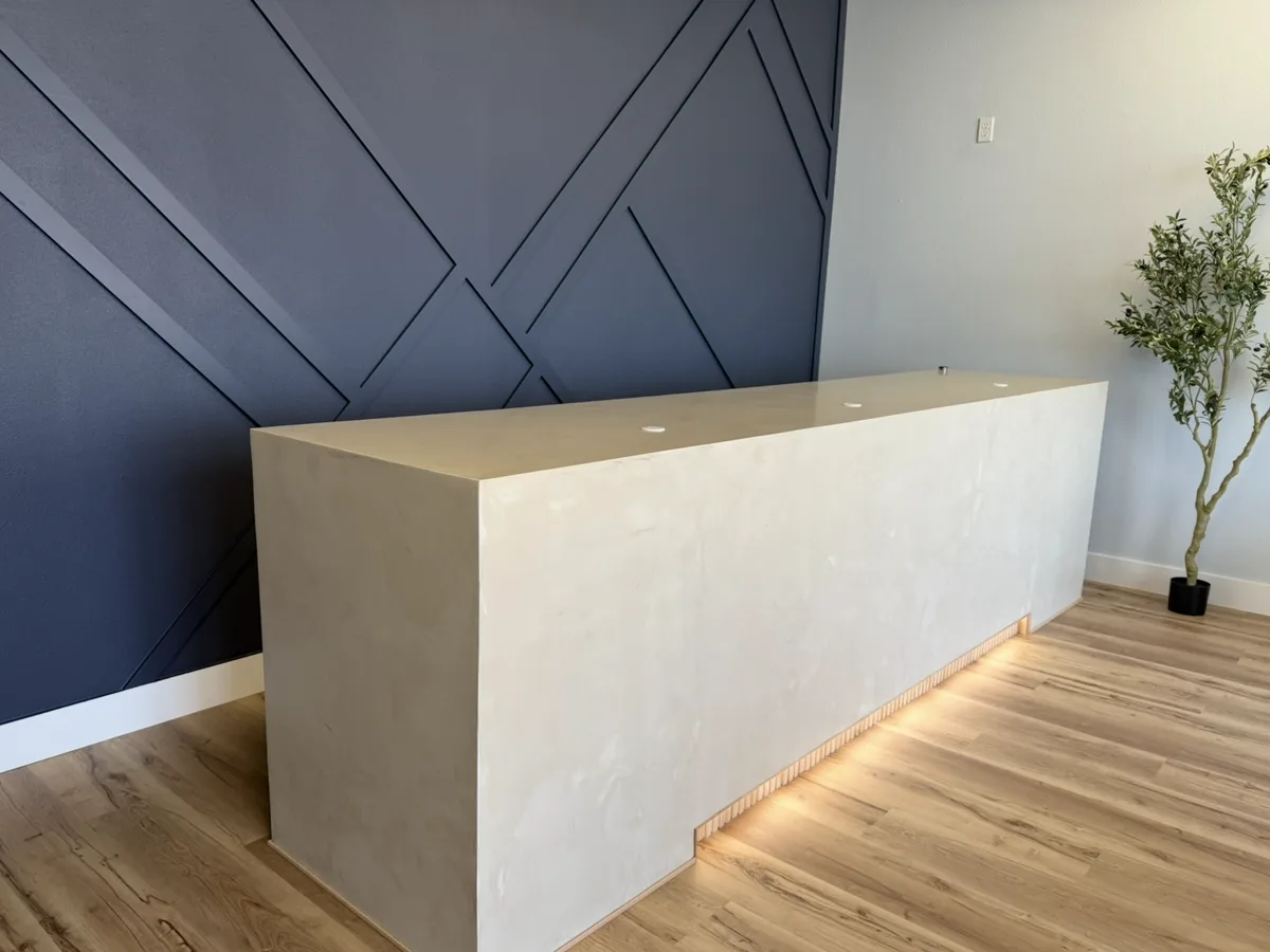 After: seamless microcement reception desk with an LED-lit toe kick in a med spa lobby
