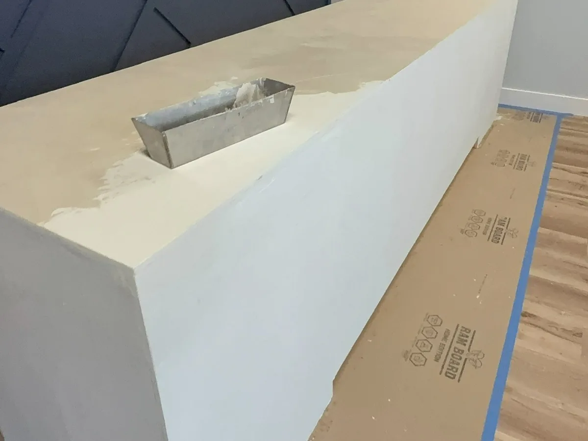 During: microcement being hand-troweled over the sheathed reception desk