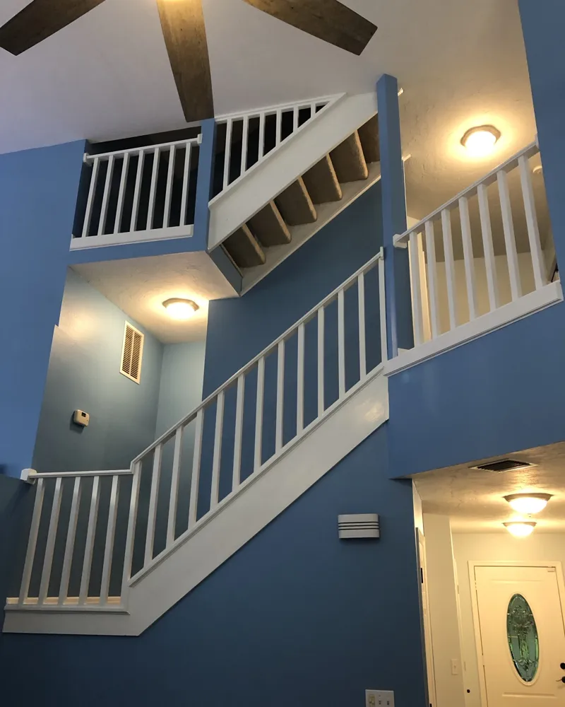 After: the stairwell painted blue with crisp white railings, balusters and trim