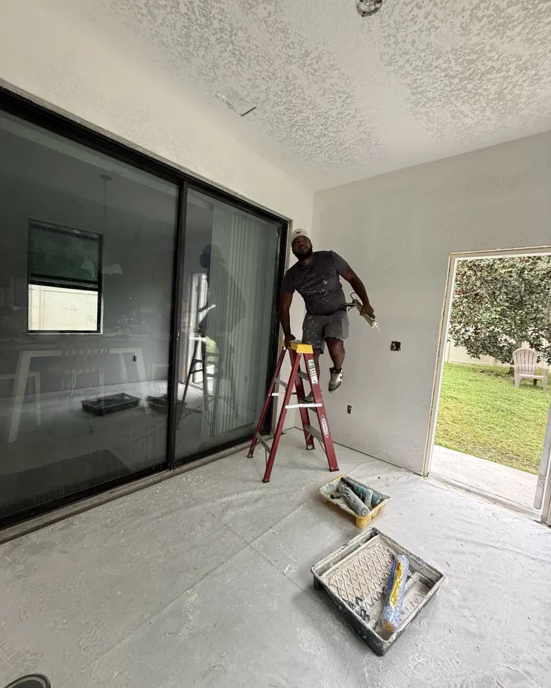 Before: new room addition with fresh textured drywall, crew caulking around the sliding door, floor protected