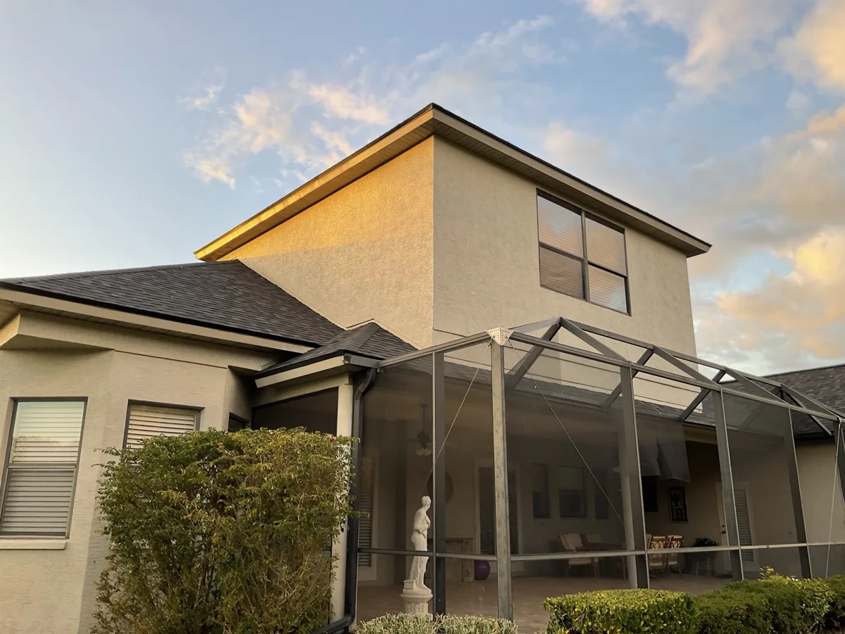After: the same two-story stucco wall freshly painted with cracks no longer visible, pool cage below