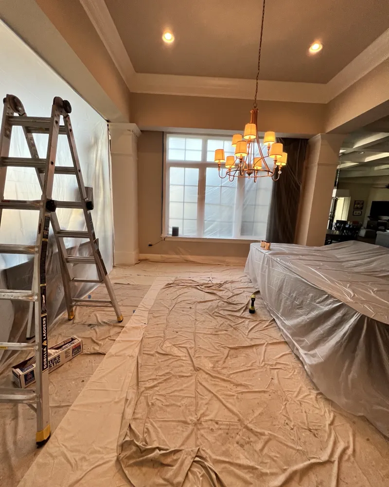 During: formal dining room with plastic sheeting on walls and windows, furniture wrapped and floors covered for drywall repairs