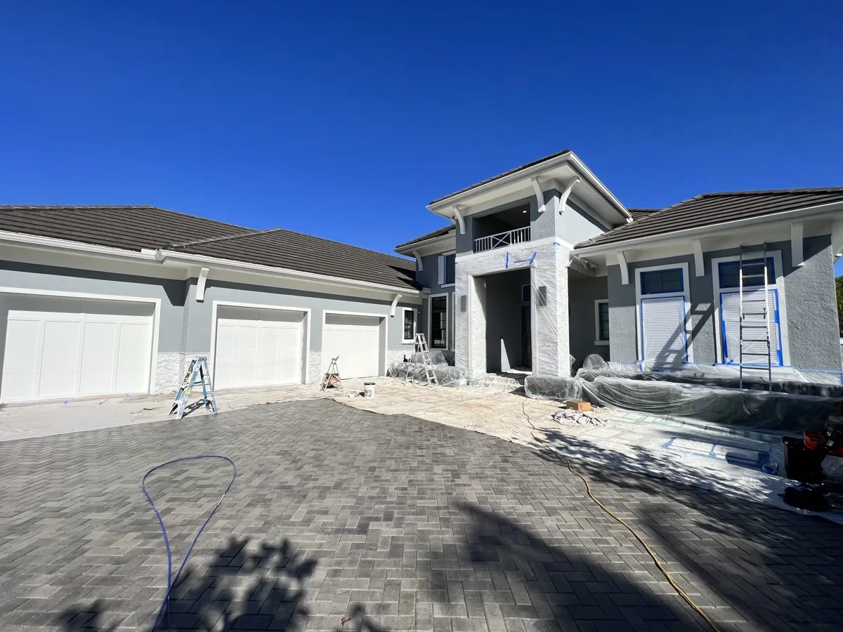 During: luxury home exterior with stone columns, shutters, windows and landscaping wrapped in plastic and paper for spraying