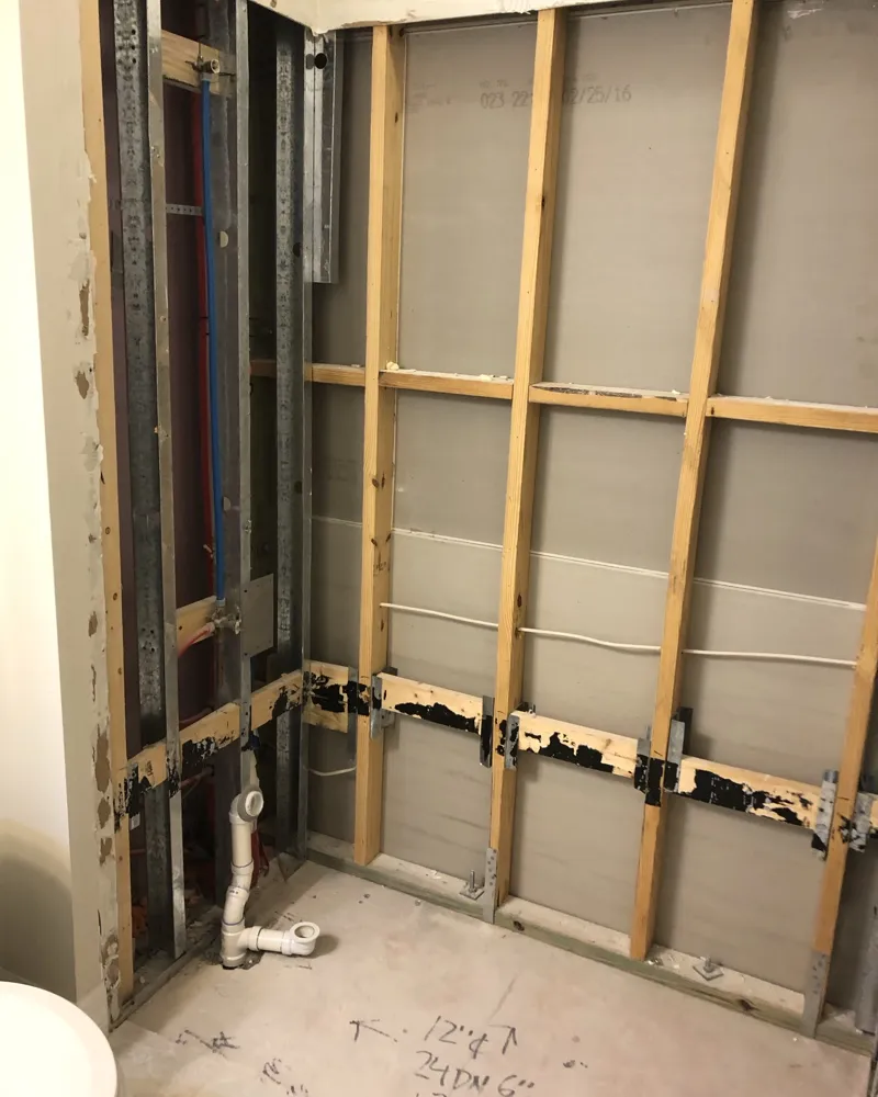 Before: shower area demolished down to the studs with plumbing exposed