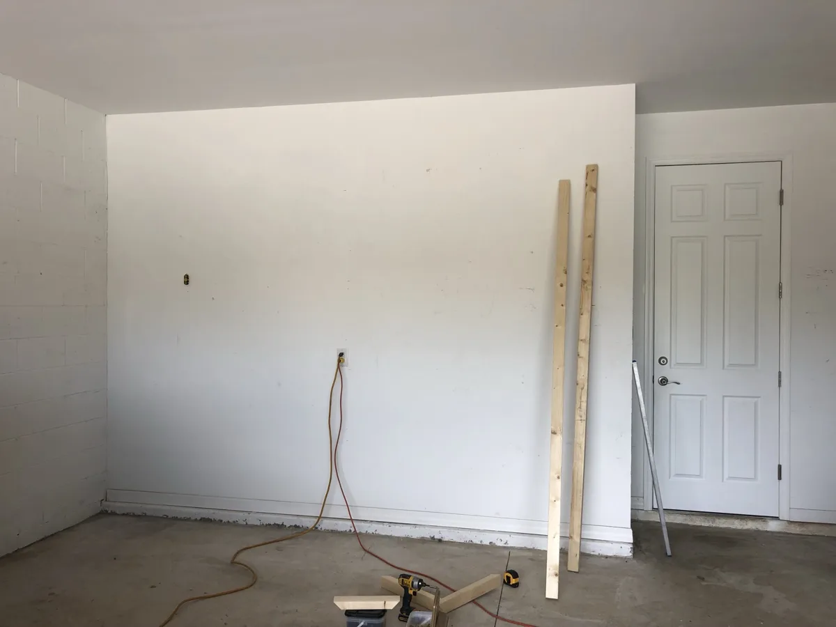Before: bare garage wall with lumber and tools ready