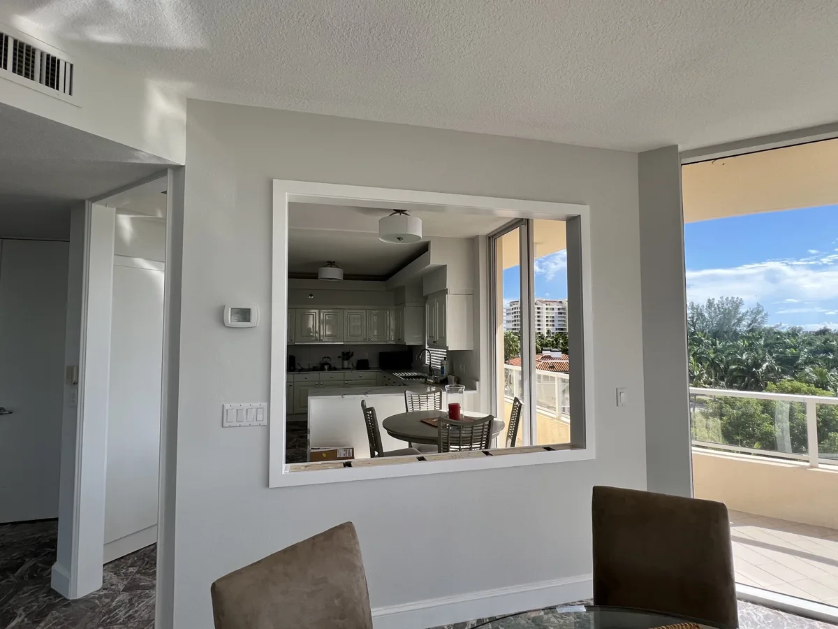 After: finished pass-through with white trim framing the view into the kitchen and out to the balcony