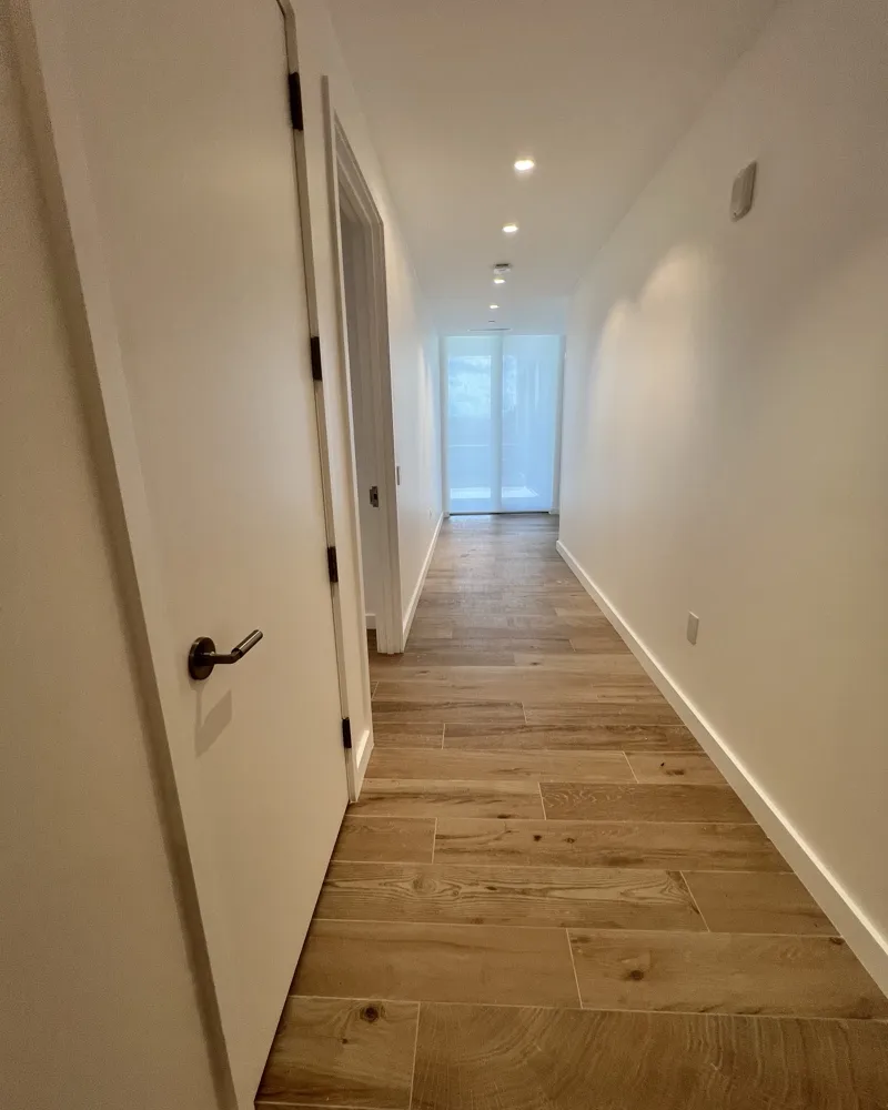 After: the same hallway with smooth, freshly painted walls and crisp white baseboards