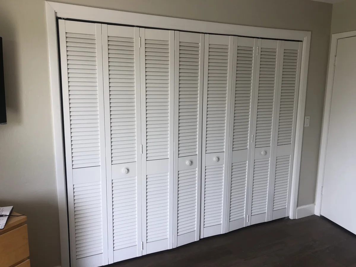 Before: wall of dated white louvered bifold closet doors