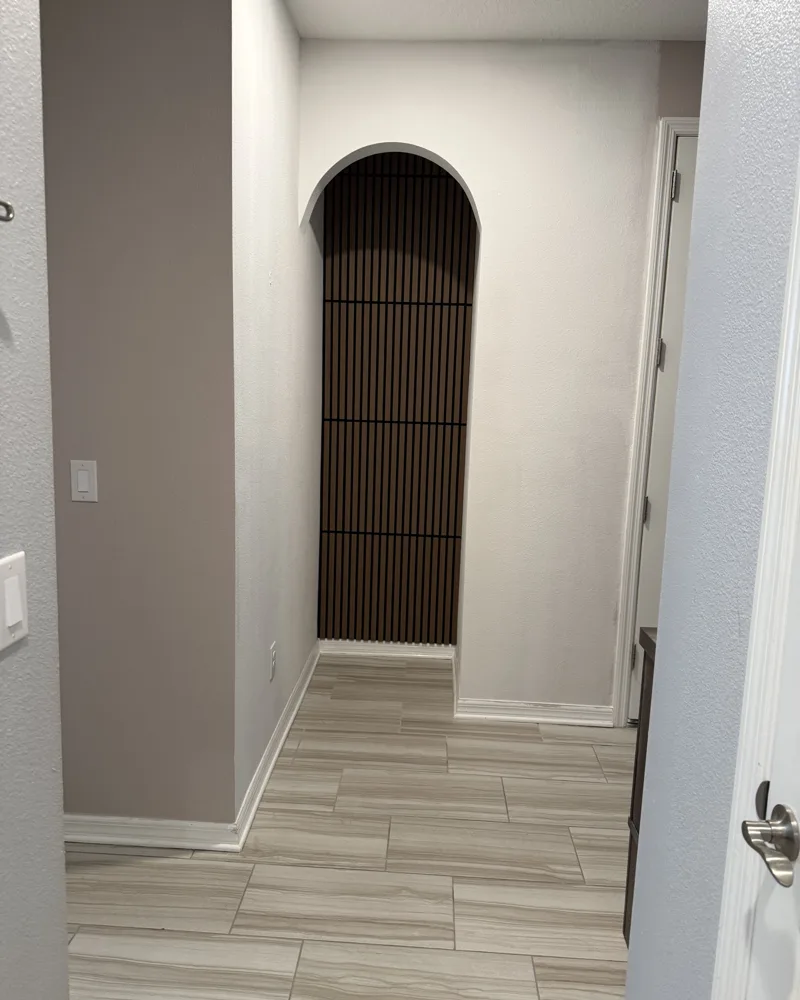 After: new rounded arch opening with smooth drywall finish and a dark wood slat accent wall inside