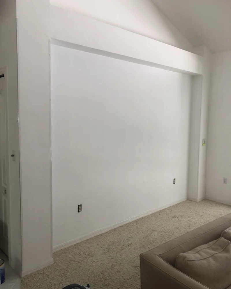 After: the same recessed wall patched smooth and freshly painted white, with no visible repairs