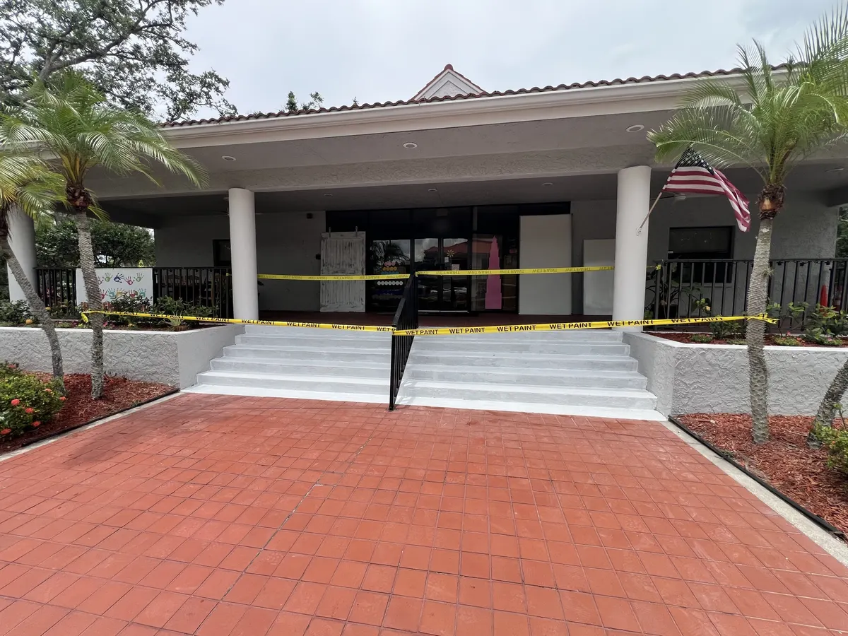 After: the same entrance steps and planter walls freshly painted, taped off with wet paint tape