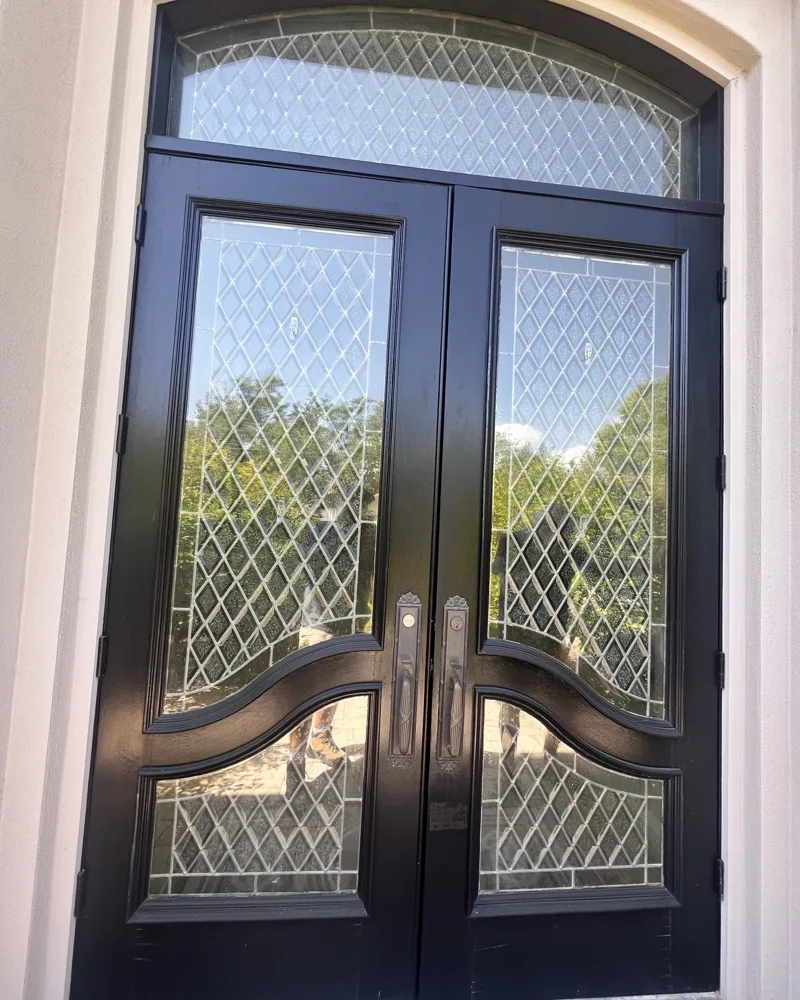 After: the same leaded-glass double doors refinished in a smooth, deep black finish