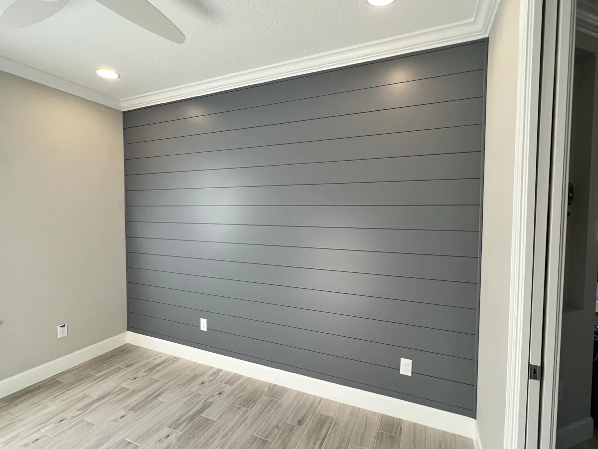 After: bedroom shiplap accent wall painted deep charcoal gray with white crown and baseboards