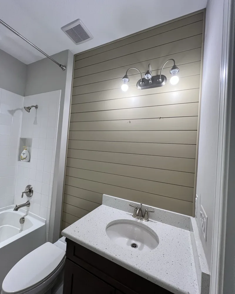 After: bathroom vanity wall finished in painted taupe shiplap behind the vanity light