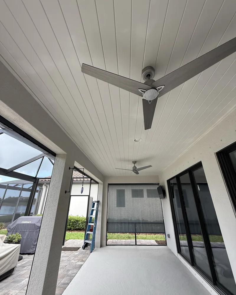 After: lanai ceiling covered in white painted PVC tongue-and-groove panels with recessed lights and ceiling fans