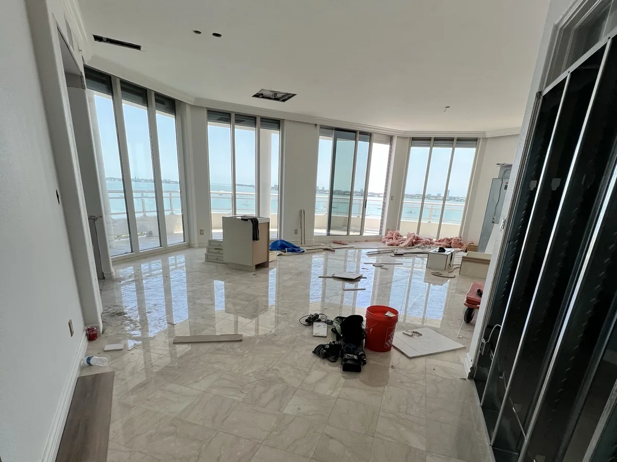 Before: bayfront high-rise condo living room during remodel, with open ceiling and walls before drywall work