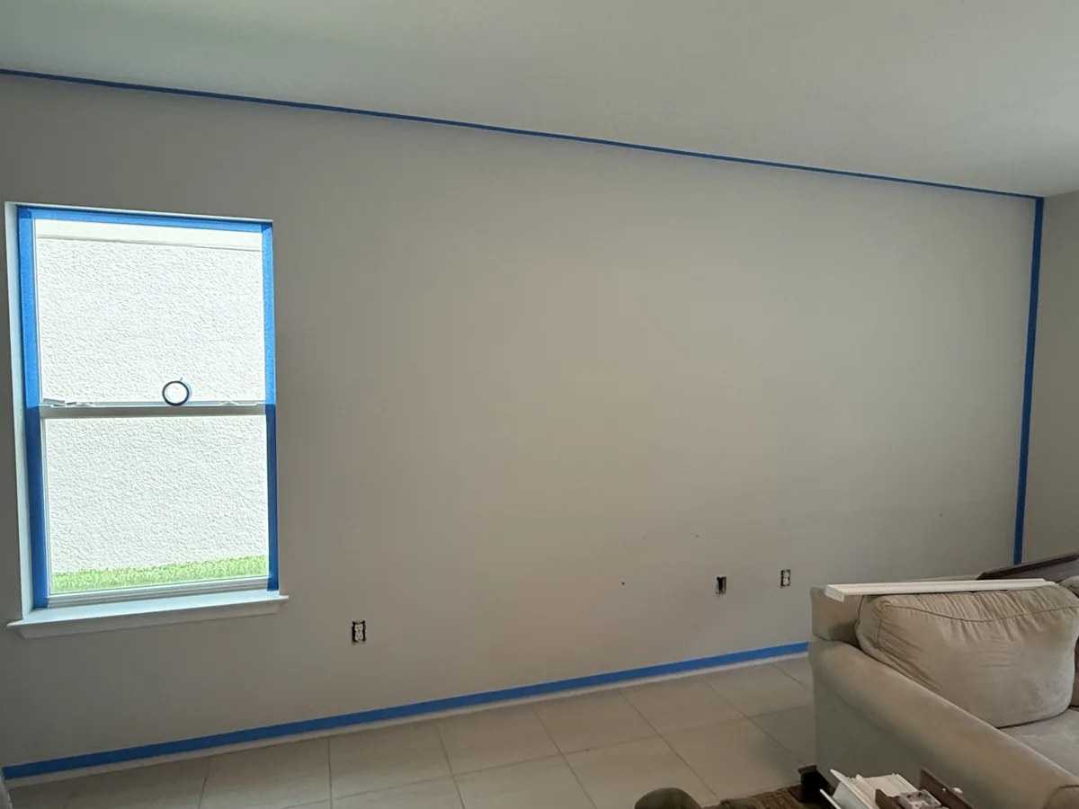 Before: plain painted living room wall taped off and ready for a decorative finish