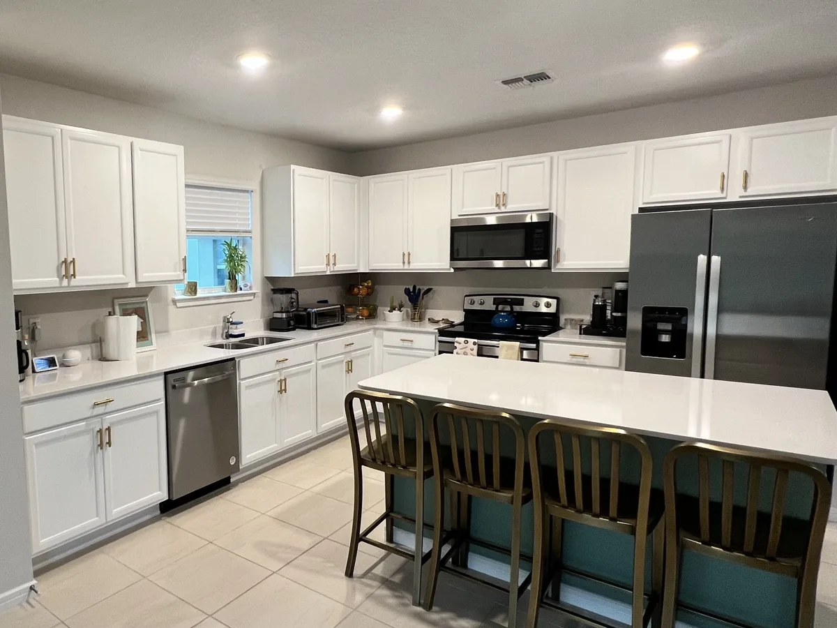 After: bright white painted kitchen cabinets with a teal island and white countertops