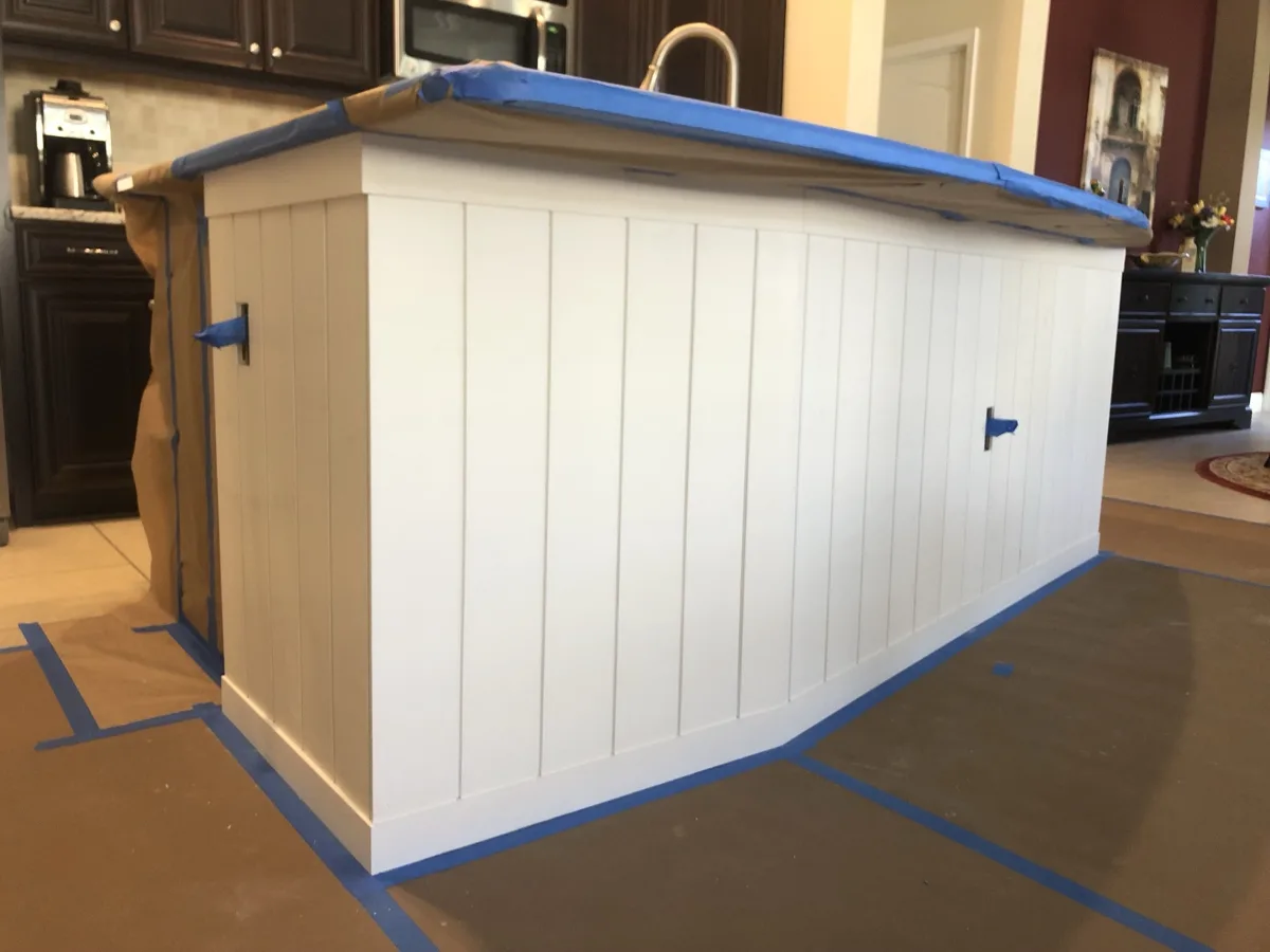 Process: vertical shiplap installed on all sides of the island and primed white, countertop and floors masked