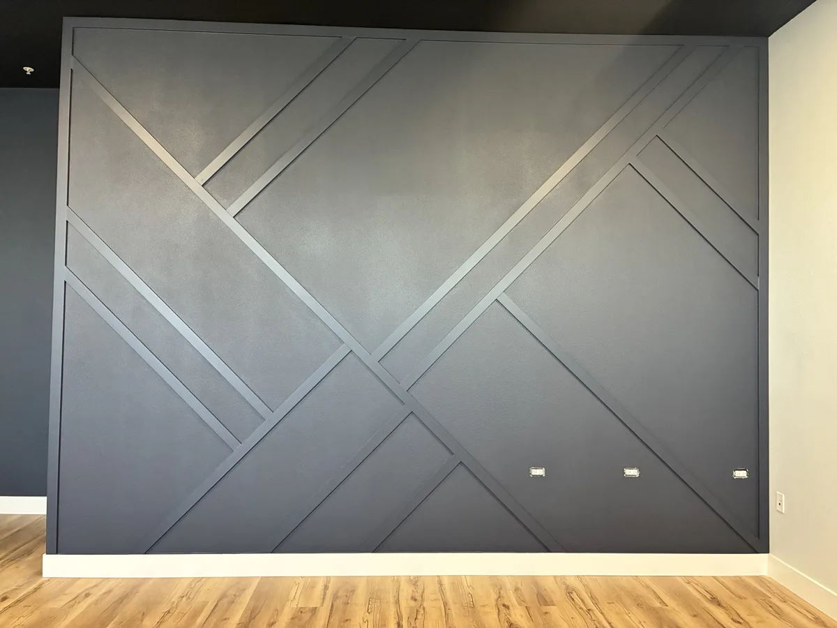 After: navy feature wall with a bold geometric diagonal trim pattern installed and painted to match